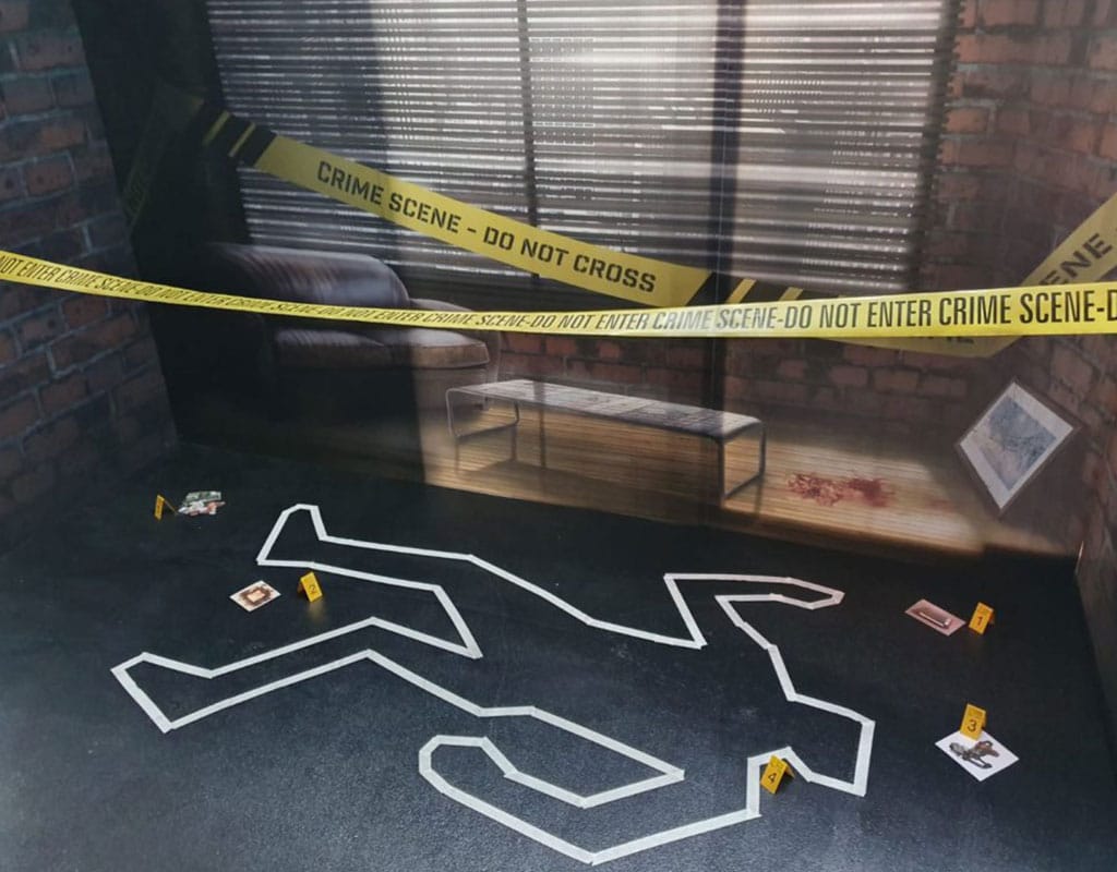 une scène de crime de murder party, au sol les contours d'un corps est délimité, on peut voir des indices numérotés un bandeau ne pas dépasser